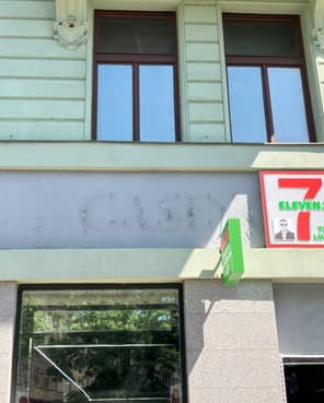 Vybledlý stín slova Casino, skrytý za cedulí obchodu s potravinami a zbylými podpůrnými tyčemi.